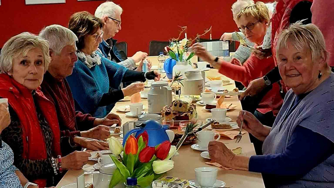 Männer und Frauen sitzen am gedeckten Tisch.