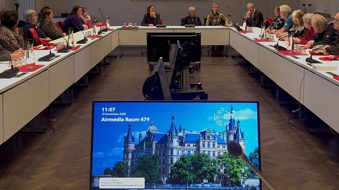 Menschen sitzen in einem Versammlungsraum.