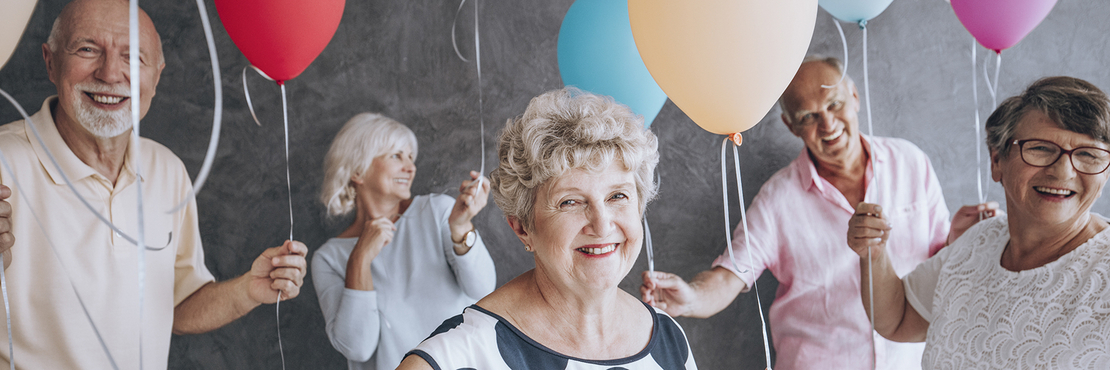 fröhliche ältere Frauen und Männer halten Luftballons in der Hand
